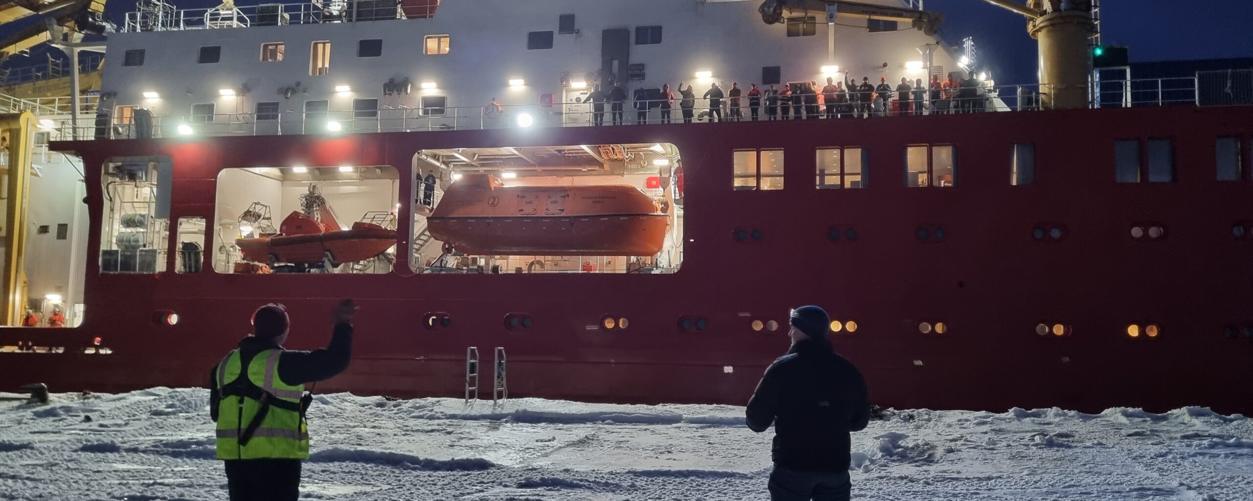 A person standing in front of a large ship in the water