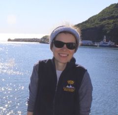 A person standing next to a body of water posing for the camera