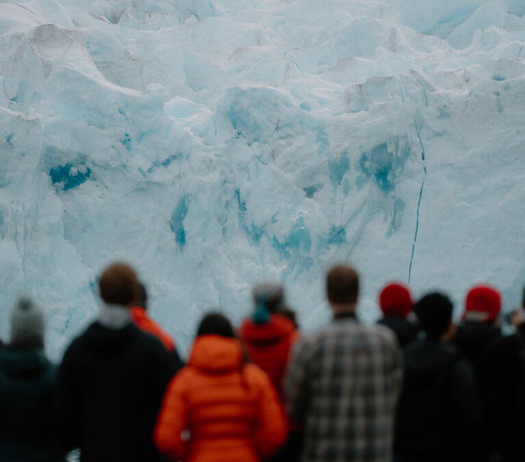 A group of people standing in front of a glacier