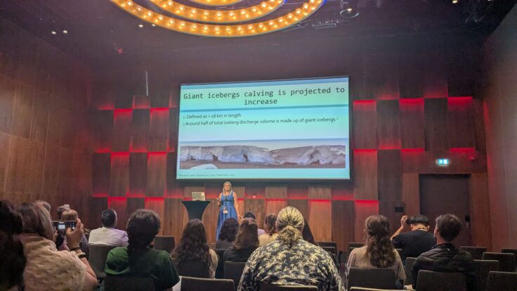 A scientist presents findings in front of a large screen.
