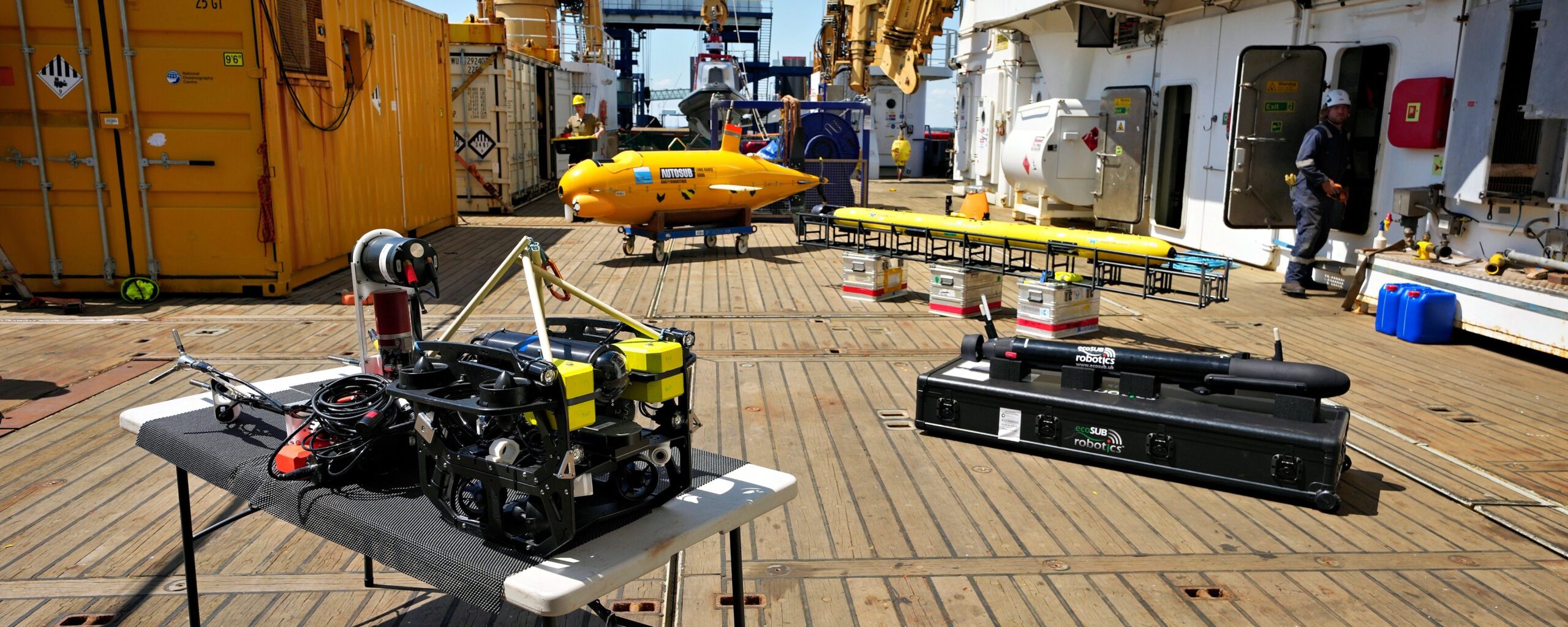 Four underwater robots are laid out on stands on the deck of a research ship.