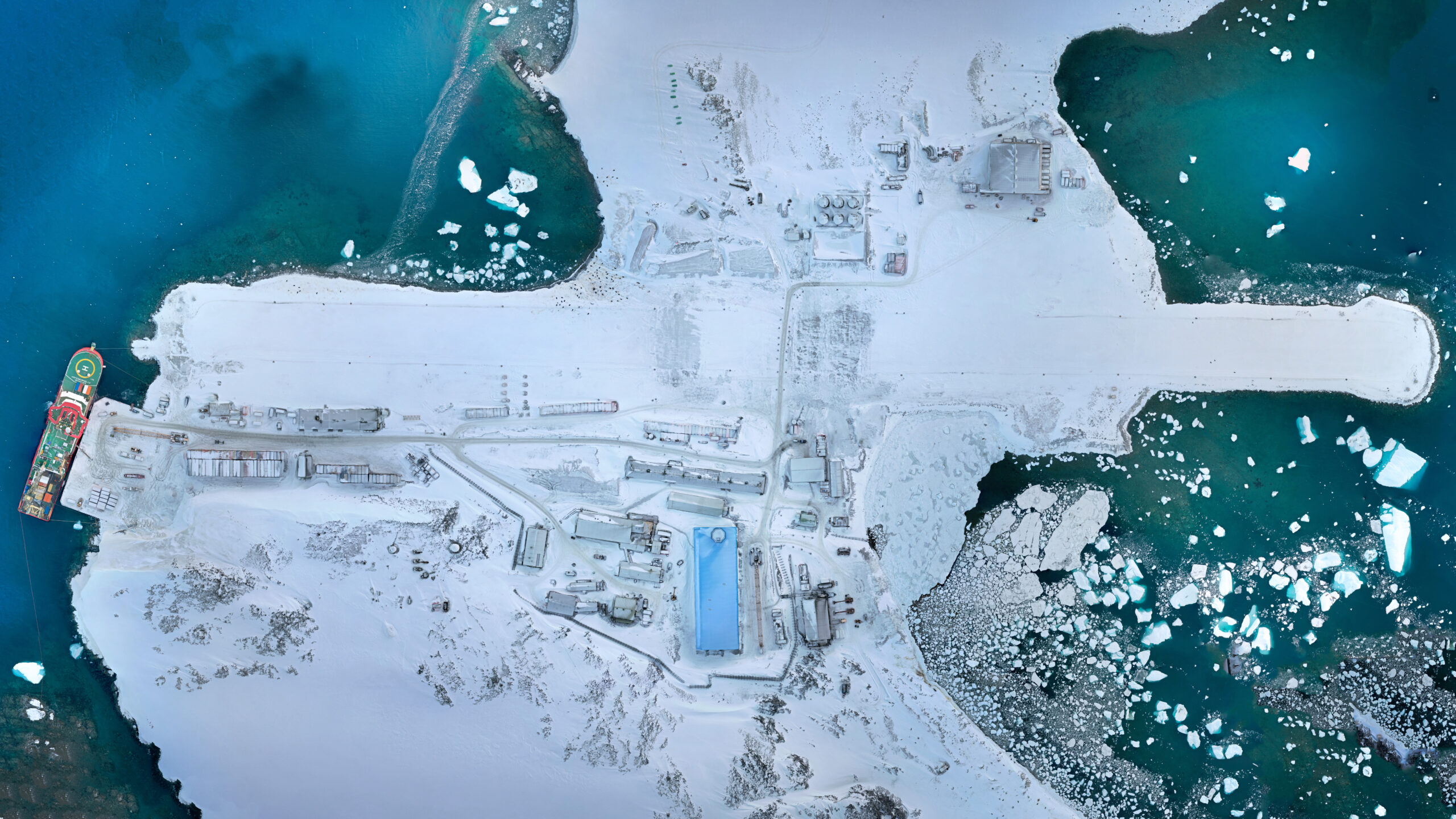 aerial view of an antarctic research station covered in snow with a large blue building