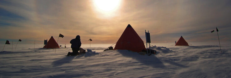 A tent in the snow with a figure in the foreground