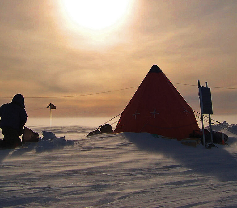 A tent in the snow with a figure in the foreground